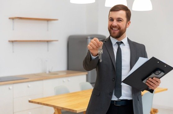 Conseiller immobilier Belgique souriant présentant les clés d’un bien immobilier prêt à emménager.